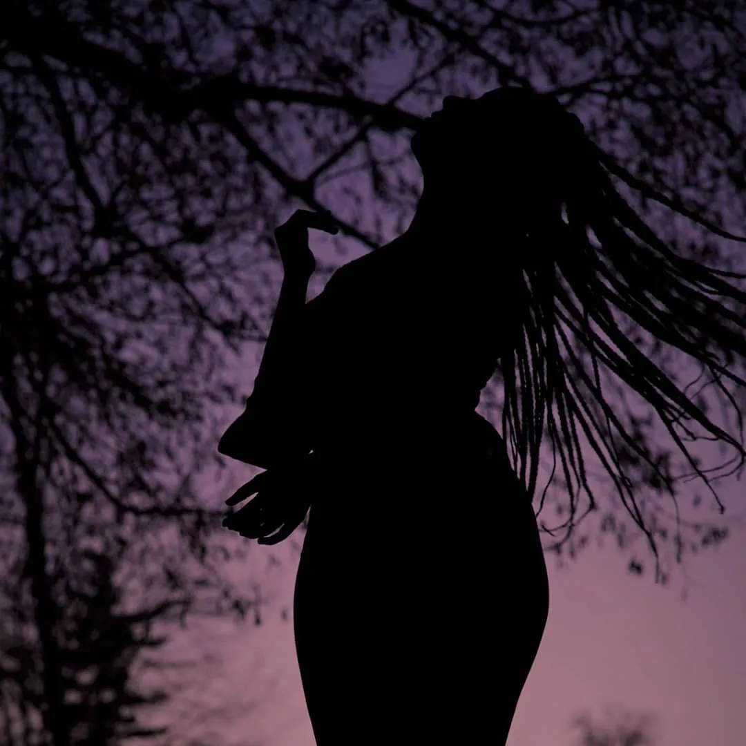 Silhouette d'une femme sous les arbres, ciel violet